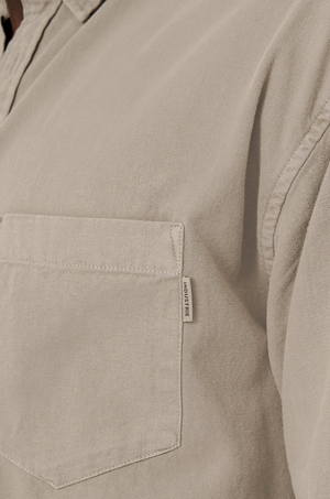Close-up of Industrie The Taylor Shirt, a beige casual shirt with a chest pocket featuring an "INDUSTRIE" label on the side. Made from 100% cotton, it has a soft, textured fabric for comfort on any occasion.