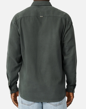 Rear view of a person in an Industrie The Taylor Shirt, dark green, 100% cotton, long-sleeve button-up with collar and logo tag. Paired with light blue jeans on a plain white background.