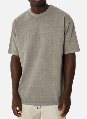 Wearing the Industrie The Del Sur Tee, an oversized gray T-shirt made of 100% cotton, paired with light-colored pants, a person stands against a plain white background.