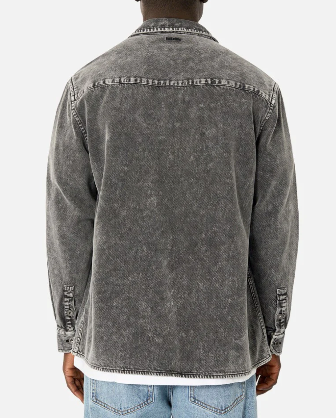 A person is wearing the comfortable Industrie The Duster Jacket in a faded black hue over a white shirt and light blue jeans. Made from 100% cotton, the jacket features a casual, worn look with buttoned cuffs. The person is shown from the back against a plain white background.