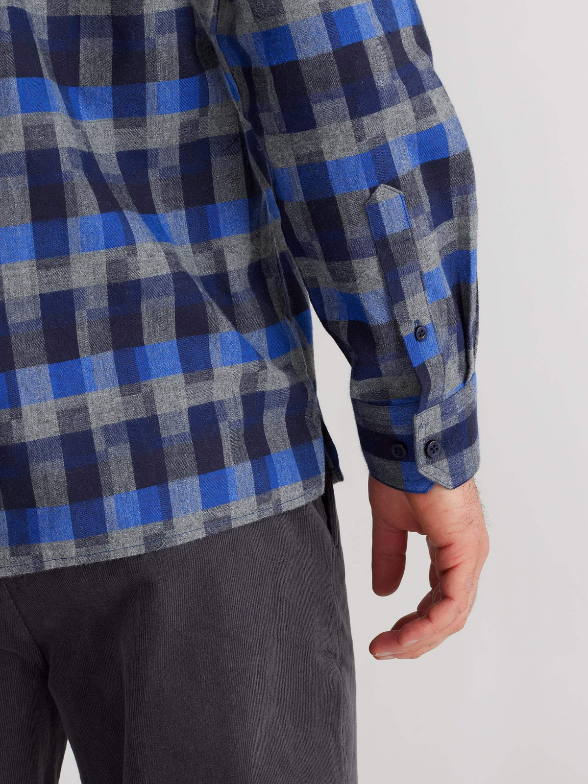 A person, shown from the back with their arm slightly bent, wears the Breakaway Benny Cotton Brush Shirt in blue and gray plaid along with dark gray pants.