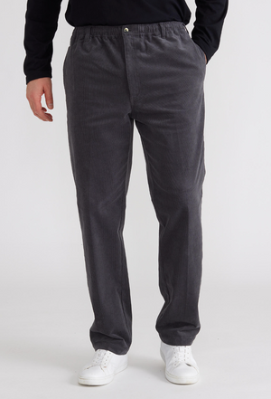 A person dons charcoal gray Breakaway Cordeaux Pants with an elastic waist, paired with white sneakers and a partially visible black top, against a plain backdrop.