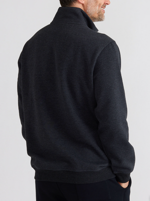 A person with short hair wears the Breakaway Bello Snowy Mt Fleece Half Zip in dark gray, long-sleeved, slightly showcasing its back. The background is plain and light-colored.