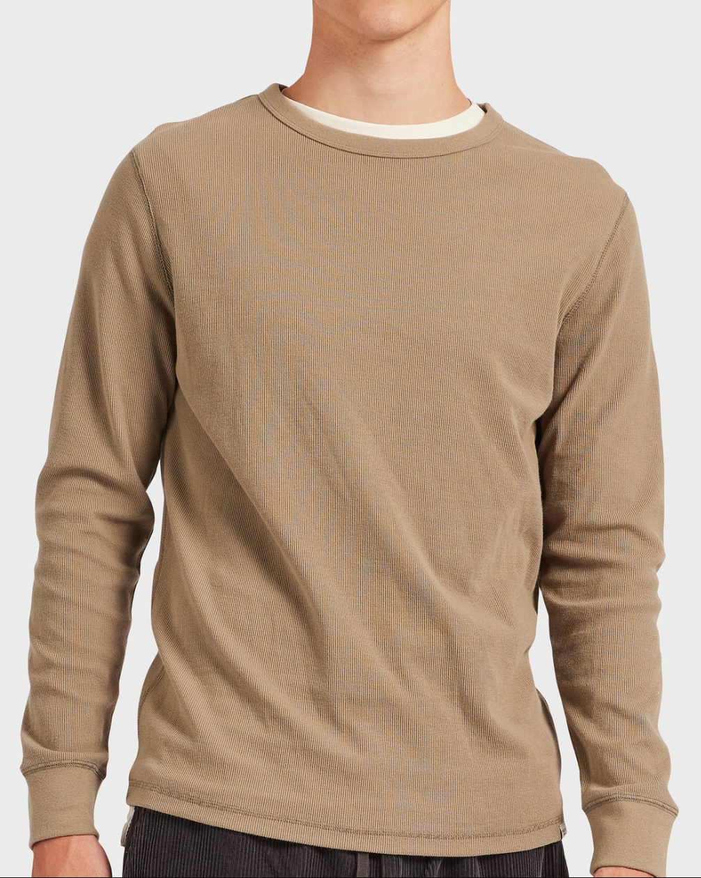 Wearing the Academy Brand Workers Crew, a light brown long-sleeve shirt with a textured pattern and comfortable crew neck, someone reveals a white undershirt at the collar while standing against a plain, light background, enjoying its relaxed fit.