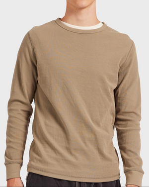 Wearing the Academy Brand Workers Crew, a light brown long-sleeve shirt with a textured pattern and comfortable crew neck, someone reveals a white undershirt at the collar while standing against a plain, light background, enjoying its relaxed fit.