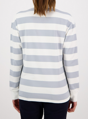 A person wearing the Swanndri Carlaw Rugby, a casual long-sleeved shirt with gray and white stripes, stands with relaxed arms and long hair. They're paired with dark pants against a plain white backdrop.