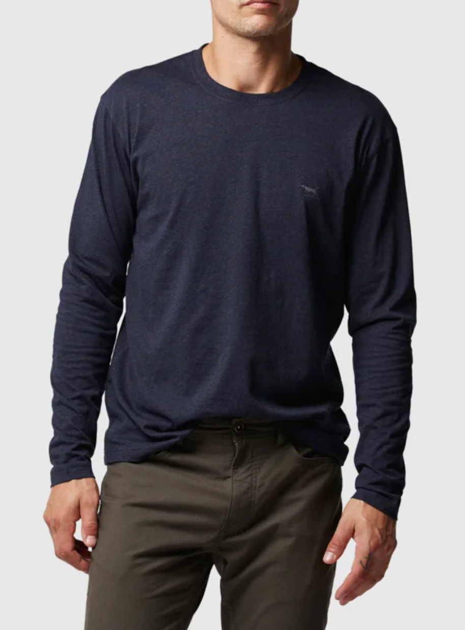 A person stands against a plain backdrop wearing a dark blue Rodd & Gunn Long Sleeve Gunn T-Shirt, featuring a sports fit and small chest logo, paired with olive green pants. Their face is unseen.