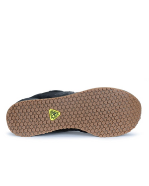 The image displays the sole of the New Balance 515 SR Shoe, which features a honeycomb tread pattern. The shoe is primarily brown with a black water-resistant oxford upper visible. At the center of the lightweight EVA midsole, there is a small yellow triangular logo.
