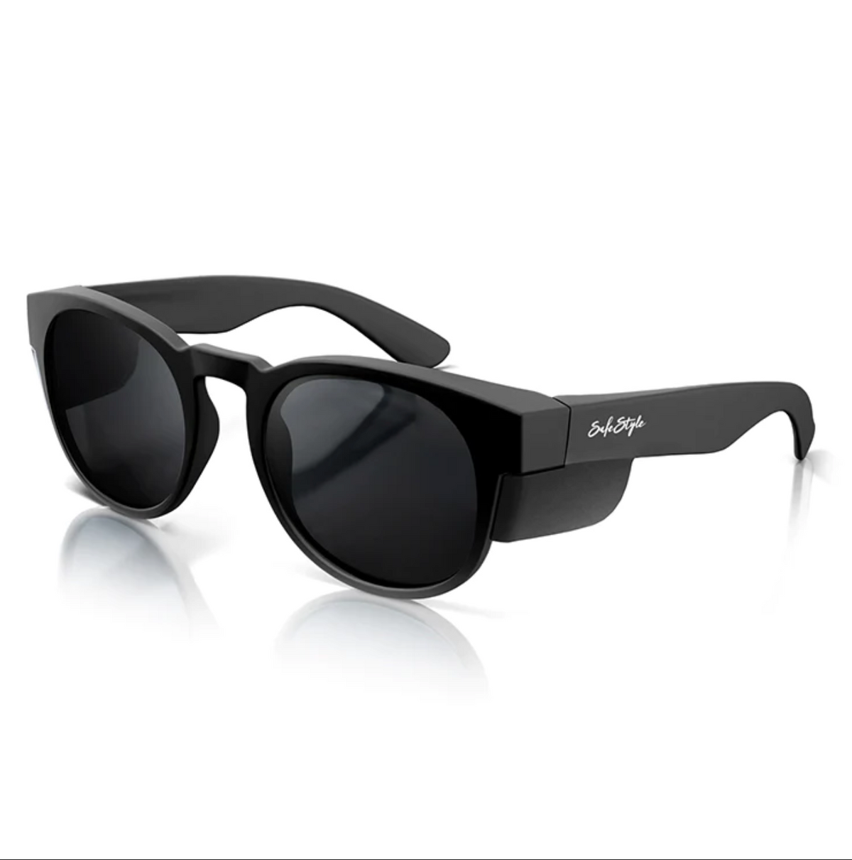The SafeStyle Cruisers Matte Black Frame Polarised Lens sunglasses feature a modern, thick frame and dark, polarised lenses. The temples display a small, white script logo on the side. Displayed on a white reflective surface, these glasses provide UV protection and exude a sleek and stylish appearance.