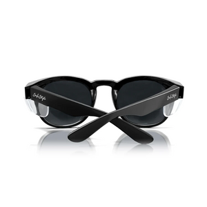 The SafeStyle Cruisers feature a chic wraparound design, glossy black frame, and polarized lenses for superb UV protection. "Solo Style" adorns the arms as they rest upright on a reflective surface.
