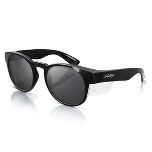 The SafeStyle Cruisers feature round tinted lenses with thick arms, providing optimal UV protection. The black frame is accented with silver sides, and the brand name appears in white on one arm. Displayed elegantly on a reflective white surface, these sunglasses are stylish and protective.