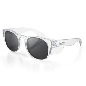 Introducing the SafeStyle Cruisers Clear Frame Polarised Lens, a pair of stylish, transparent frame sunglasses featuring dark, oval-shaped lenses with UV protection. The left arm boasts a black text logo for added branding appeal. These fashionable sunglasses are elegantly displayed on a white surface.