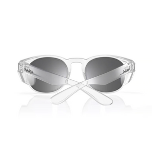 The SafeStyle Cruisers feature clear frames and tinted lenses with a reflective finish viewable from the front. The crossed arms showcase a signature on one side, offering UV protection while contrasting elegantly with the transparent frame.
