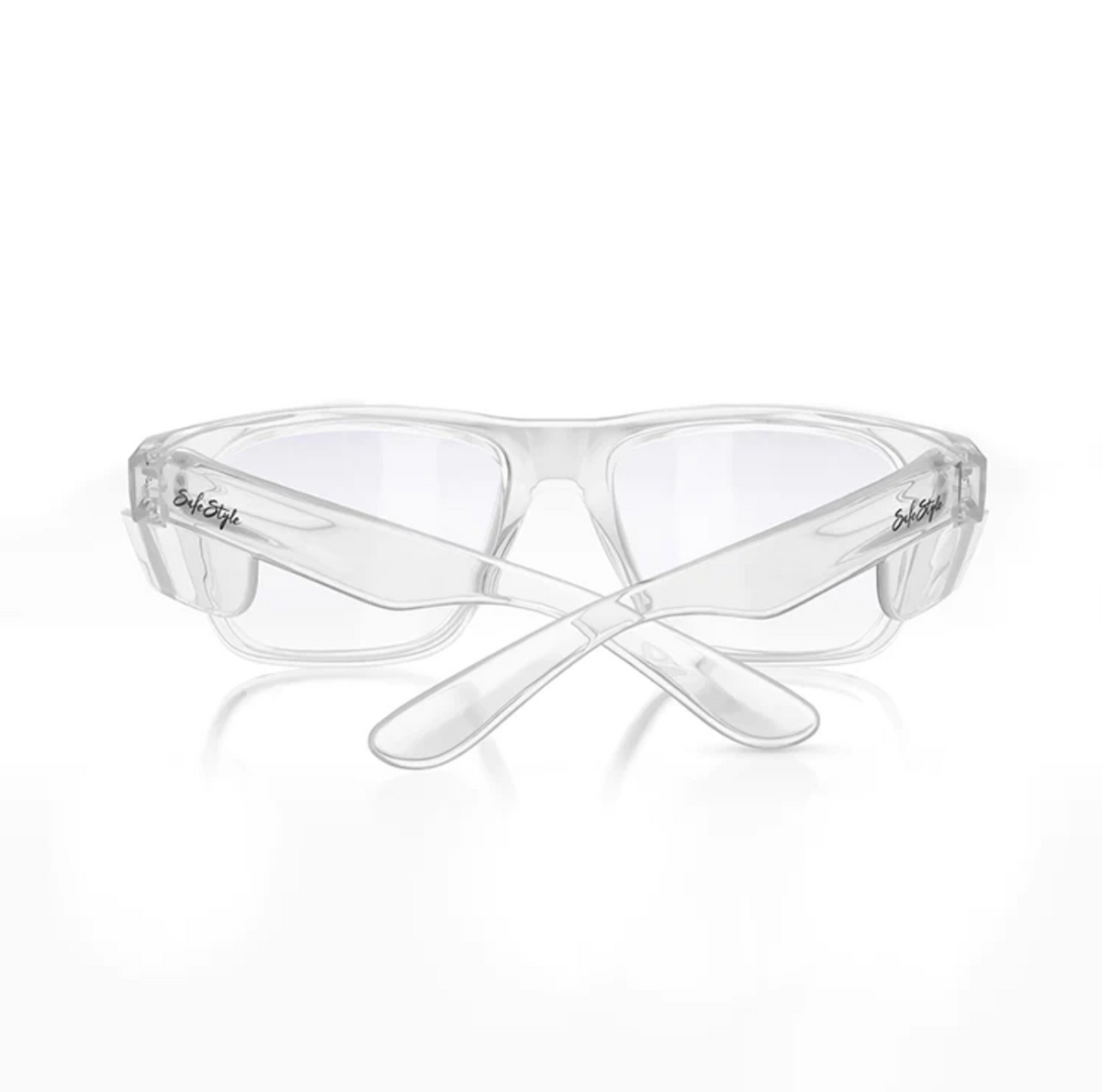 The SafeStyle Fusions clear eyeglasses feature a logo on the temples. Designed for safety, the transparent polycarbonate frames and lenses offer UV protection. The earpieces cross underneath, shown from the back angle.