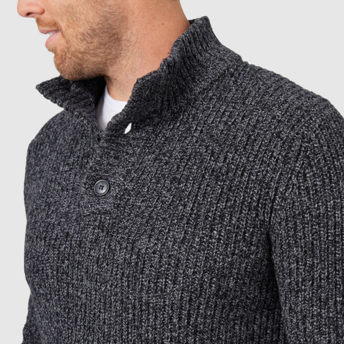 Someone wearing the dark gray Blazer Oscar Button Neck Knit over a white shirt. The image focuses on the sweater's upper half, showcasing its intricate textured knit pattern and high collar.