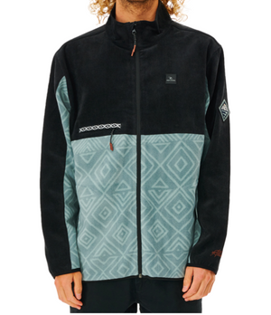 A person wearing a Rip Curl Anti Series Journey Fleece with a high collar. The water-repellent jacket features a black upper and sleeves, teal lower section with geometric diamond pattern, zippered pockets, small logo on the chest, and patterned strip near the left pocket.