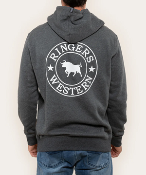 A person wears a dark gray Ringers Western Signature Bull Hoodie with its hood up. The white circular logo with a bull is visible on the back, complementing their blue jeans.