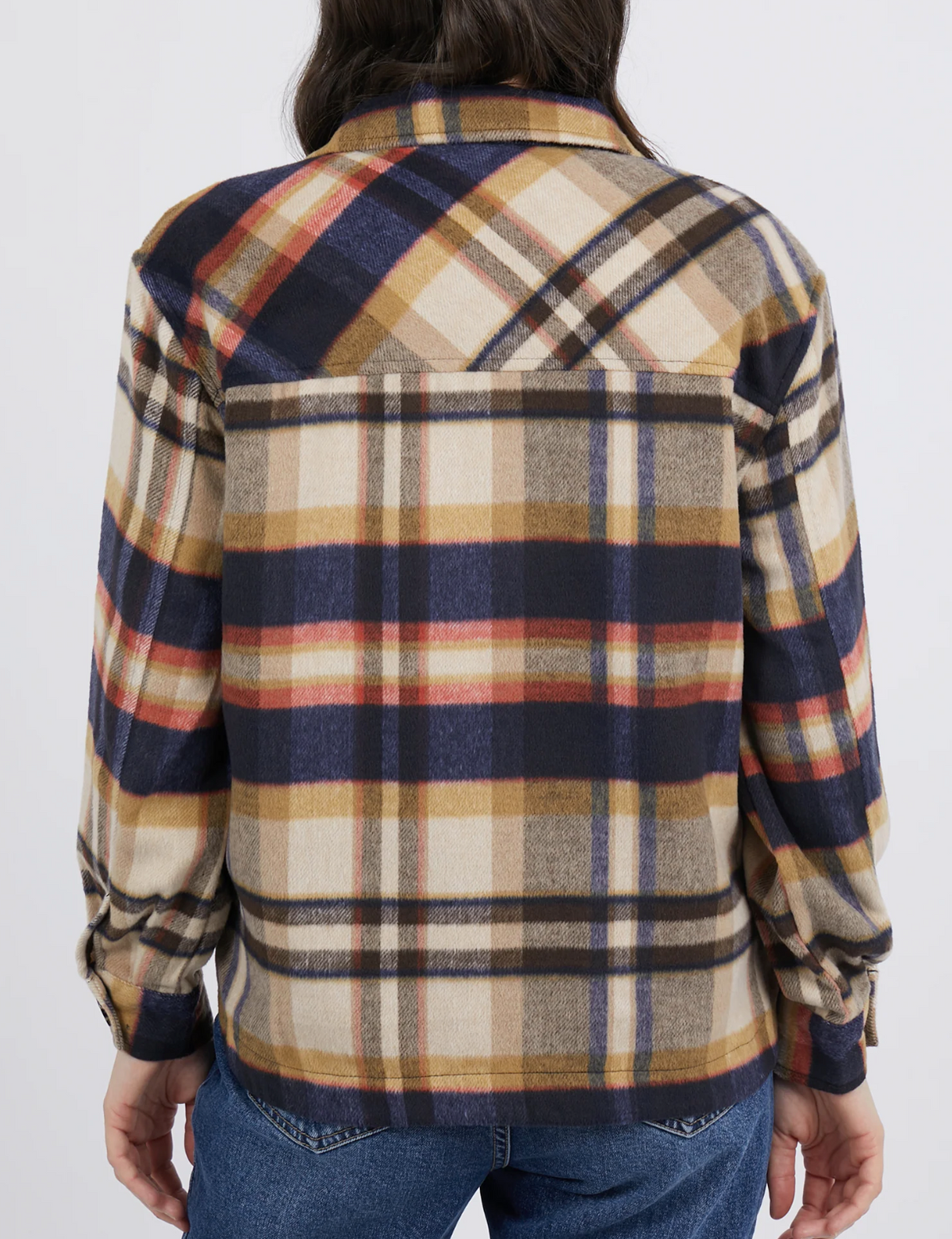 A person with long hair is seen from behind on a plain white background, wearing the Foxwood Noemi Check Shacket in blue, beige, and orange plaid. It's styled as a classic-collared shirt paired with comfortable blue jeans.