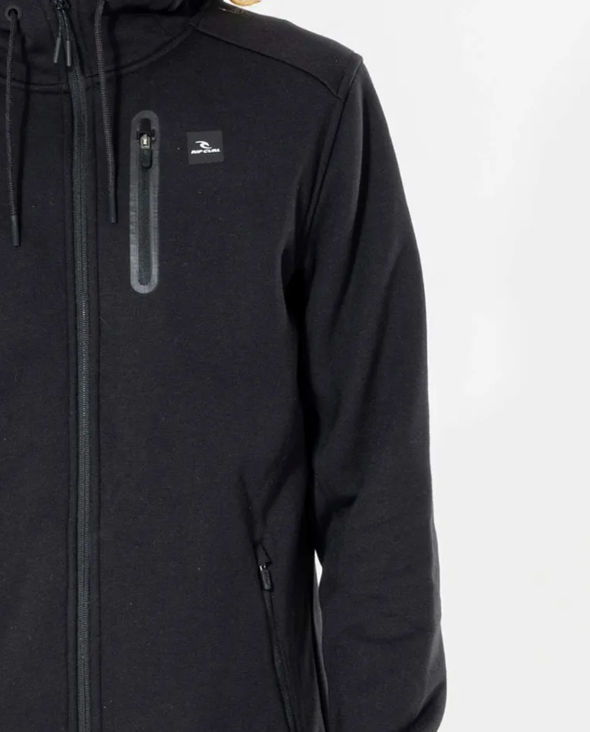 The Rip Curl Anti Series Departed Zip Thru is a black hooded jacket featuring a water-resistant finish, full-length zipper, and small zippered chest pocket on the left. It includes a subtle logo near the pocket and is ideal for winter, displayed against a plain background.
