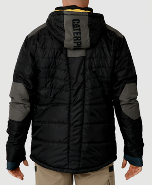 A person wearing a CAT Triton Insulated Puffer Jacket, featuring storm blocker technology and a hood, stands with their back to the viewer. The black and gray jacket has "CATERPILLAR" printed on the back, paired with khaki pants.