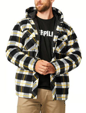 A person adjusts the cuff of a CAT Active Work Jacket, featuring black, white, and yellow plaid and adjustable cuffs. They pair it with a black text shirt and beige pants while looking to the side.
