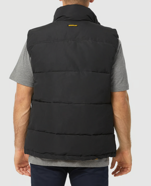 Rear view of a person wearing a black CAT Arctic Zone Vest, featuring a water-resistant finish, branded upper back, and insulated collar over a gray T-shirt. Paired with dark pants, they stand against a plain, light-colored background.