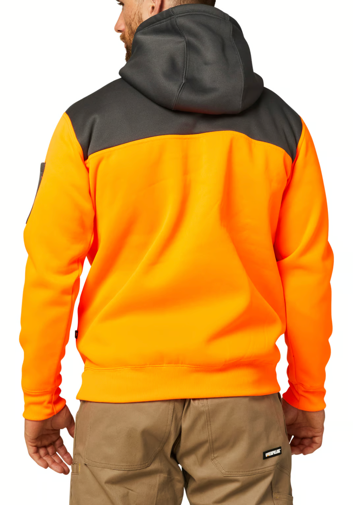A man wears a high-visibility orange and dark gray CAT Hi Vis Hoodie, featuring a cozy fleece lining and large hood, stands with his back to the camera. He pairs it with khaki work pants, hands by his sides.