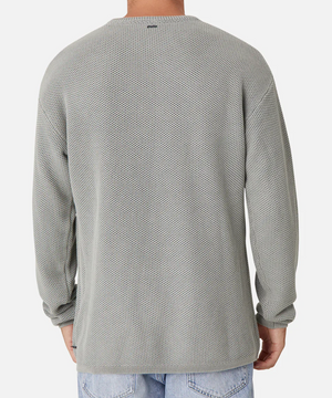 Seen from the back, a person is wearing a gray Industrie The Washed Culver Knit long-sleeve shirt with a waffle texture and relaxed fit, made from 100% cotton. It pairs effortlessly with light blue jeans against a plain white background.