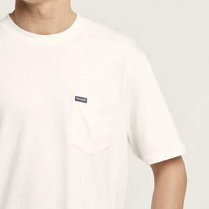 A person is wearing a Wrangler Classic Pocket Tee, featuring a plain white design with a small chest pocket and a tiny rectangular label. The image is cropped at the neck and mid-arm, highlighting the simplicity of this 100% cotton shirt.