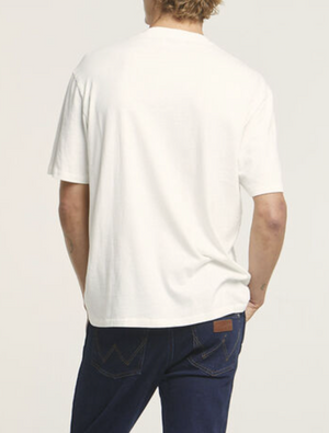 A person is seen from the back wearing a Wrangler Classic Pocket Tee made of 100% cotton paired with dark blue jeans featuring visible pocket stitching against a neutral, light gray background.