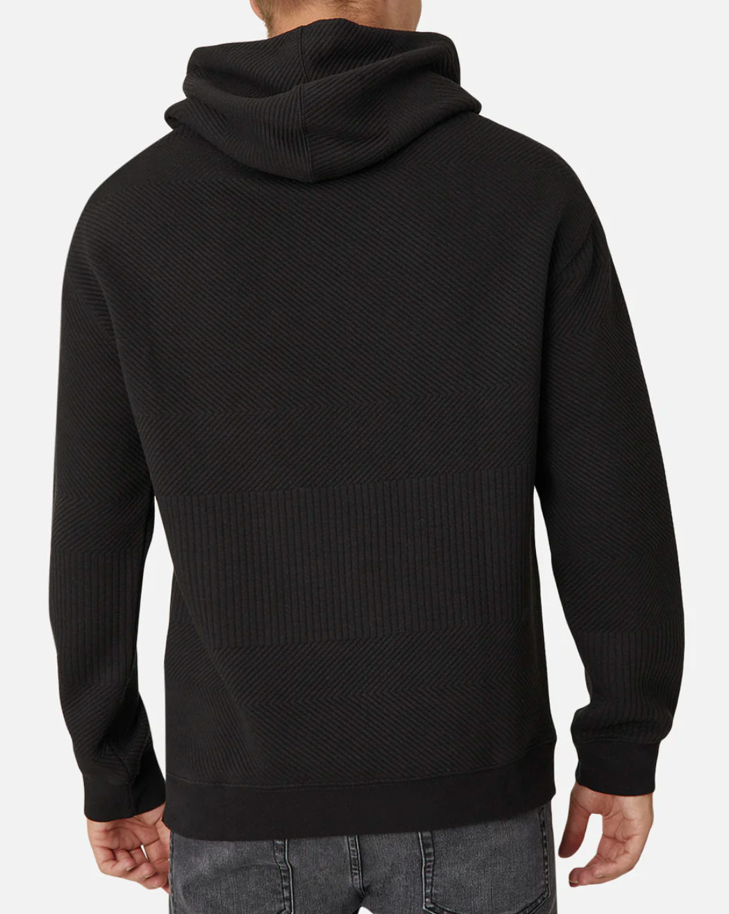 A person wears the Industrie The Robinson Hoodie, featuring a relaxed fit and subtle textured design in black. They pair it with casual gray jeans, standing against a plain white background with their back to the camera.