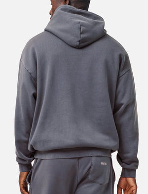 A person is seen from behind wearing the Industrie The Del Sur Hoodie in acid wash gray, paired with matching sweatpants. The loose-fitting hoodie features a hood, while the sweatpants have an embroidered text on the back pocket. They stand against a plain light gray background.