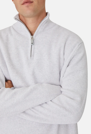 A person is shown from shoulders to waist, arms crossed, wearing the Industrie The Lakewood Zip Neck—a light gray 100% cotton jumper—against a plain background.