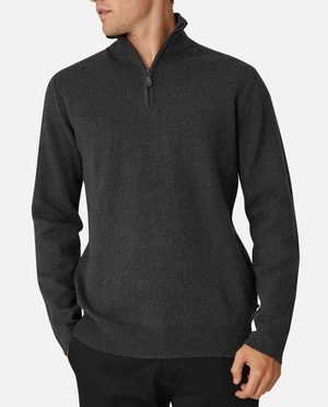 Someone wearing an Industrie The Lakewood Zip Neck, a dark gray sweater with ribbed cuffs and hem, and black pants stands against a white background. Made from 100% cotton, the casual jumper's wearer has their hands in their pockets and is looking to the side.