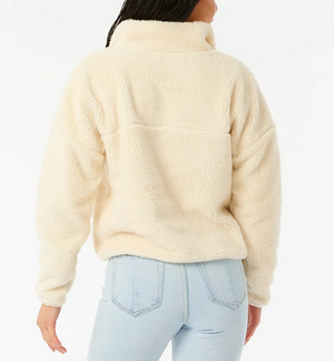 Someone is seen from the back against a white background, wearing a cream-colored Rip Curl Supply Button Up Polar Fleece and light blue high-waisted jeans.