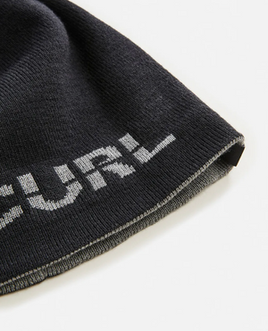 A close-up of a black Rip Curl Cutback Revo Beanie with partial white "URL" text near the edge, featuring a reversible design, displayed on a white background.