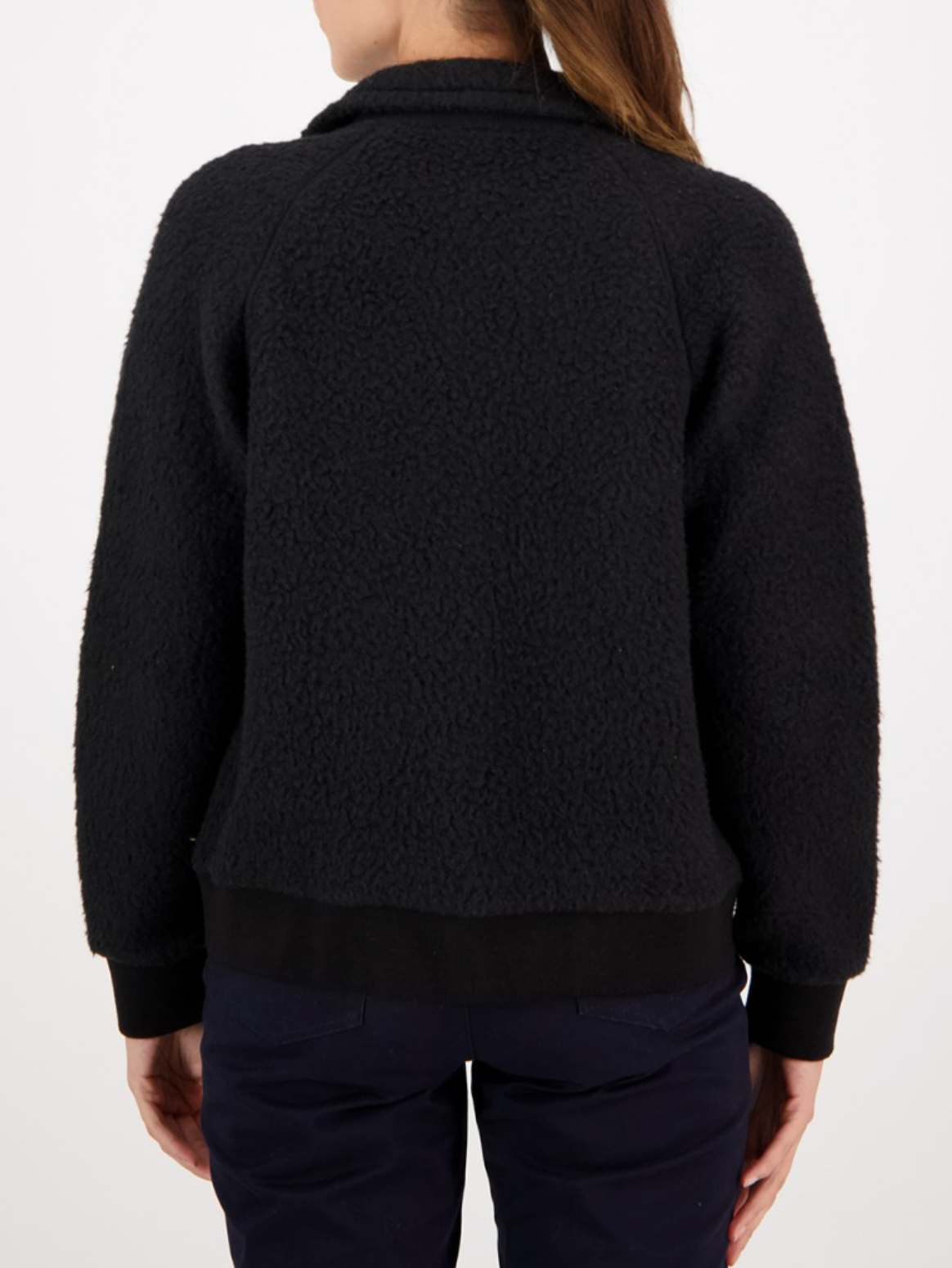 A person is viewed from behind in a cozy Swanndri Newgate Wool Fleece Jacket with long sleeves. Their hair is tied back, and they wear dark pants, set against a minimal white background that accentuates the jacket's textured warmth.