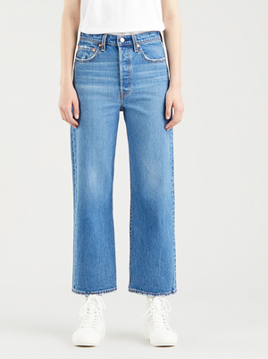 A person wearing Levis Ribcage Straight Jeans in light blue and a white shirt is styled with white lace-up ankle boots, standing against a plain white background.