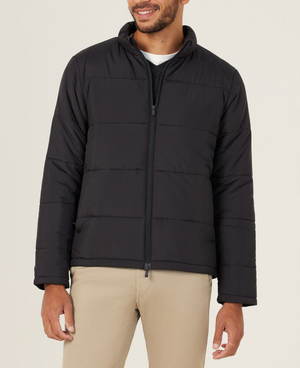 A man wearing a stylish NNT Puffer Jacket with 3M Thinsulate over a black shirt and beige pants stands against a plain light background, smiling slightly.