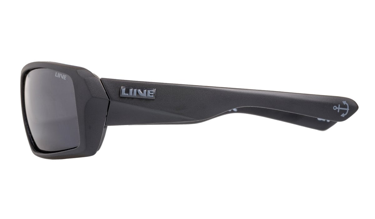A pair of black Liive The Edge Polar Float Sunglasses with a chunky, angular frame. The temples feature a brand logo "LINE" in raised silver lettering and a small anchor symbol. The polarised grey lenses offer UV protection and full coverage, ensuring style and safety.