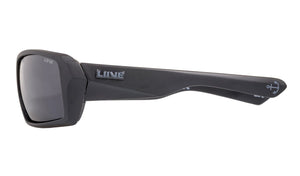 A pair of black Liive The Edge Polar Float Sunglasses with a chunky, angular frame. The temples feature a brand logo "LINE" in raised silver lettering and a small anchor symbol. The polarised grey lenses offer UV protection and full coverage, ensuring style and safety.