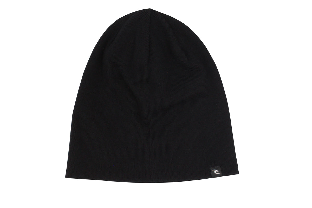 The Rip Curl T-Street Skull Beanie, a sleek black hat featuring a roll cuff and a subtle logo tag on the edge, is showcased against a pristine white background.