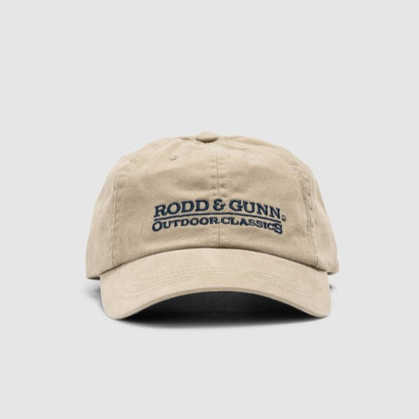 The Rodd & Gunn Marsden Point Cap is made from cotton twill and comes in beige with "Rodd & Gunn Outdoor Classics" in black on the front. It features an adjustable strap for comfort, set against a plain white background.
