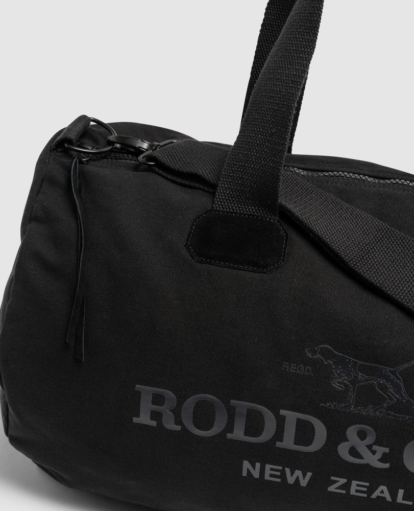 The Rodd & Gunn Richmond Road Duffle Bag is a black cotton canvas bag with sturdy handles and a zipper closure, featuring the "RODD & GUNN NEW ZEALAND" printed logo next to a dog image.