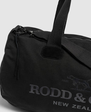 The Rodd & Gunn Richmond Road Duffle Bag is a black cotton canvas bag with sturdy handles and a zipper closure, featuring the "RODD & GUNN NEW ZEALAND" printed logo next to a dog image.
