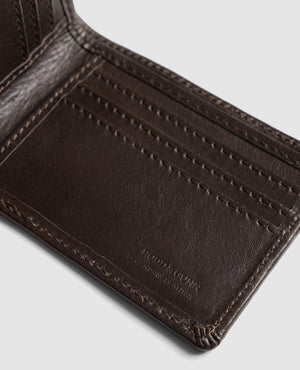 A close-up of an open dark brown leather wallet, the Rodd & Gunn Victoria Flats Road Wallet, crafted from Genuine Buffalo Leather, showing multiple card slots. The interior stitching and leather texture are clearly visible. The bottom right corner is embossed with the text "BEDFORD & SLINK MANHATTAN.