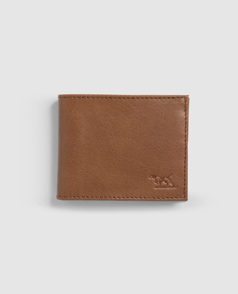 A tan-colored Rodd & Gunn Leeston Dunsandel Road Wallet made of Genuine Buffalo Leather is shown against a plain white background. The wallet features a small embossed dog logo in the bottom right corner and has stitched edges. With multiple card slots and a buttoned coin pocket, the sleek design is closed and smooth.