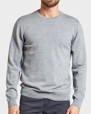 A person wearing the Academy Brand Academy Merino Crew stands against a plain, light background. Their light gray crew neck jumper, crafted from premium Australian Merino Wool, pairs perfectly with dark pants, while their face is partially cropped out of the frame.