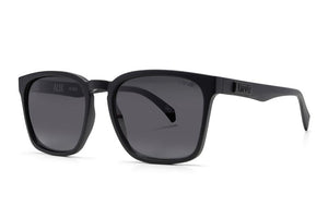 A pair of Liive Alik Sunglasses featuring black square frames, dark UV-protected polycarbonate lenses, and sleek, thick temples. One temple is adorned with a raised logo. The modern, minimalist design makes them ideal for both casual and formal occasions.