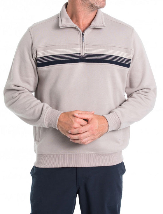 A man is wearing a "Breakaway Leo Snowy Mt Fleece Half Zip" in light beige with horizontal navy stripes across the chest. He is standing against a plain white background with his hands clasped in front of him, also dressed in dark blue pants. While his face isn't visible in the image, this winter staple radiates warmth and style.